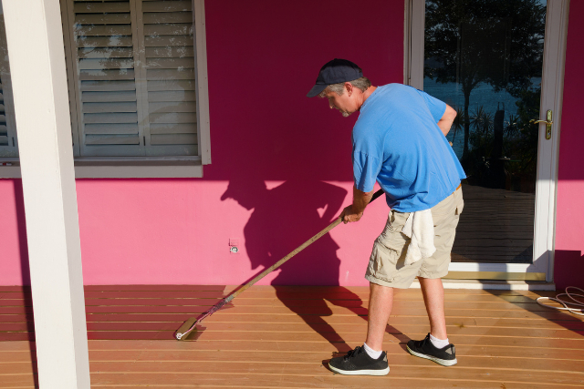 Worker painting staining wooden deck