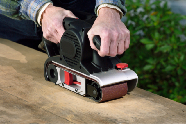 Portland Worker sanding down the deck with electric sander